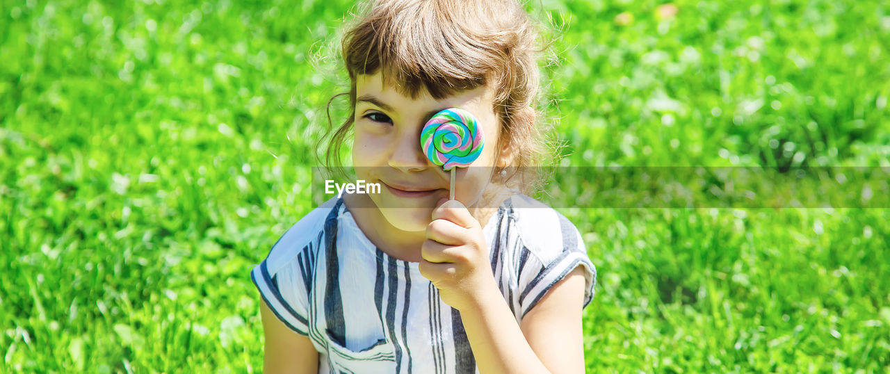 Portrait of girl holding lollipop in front of eye