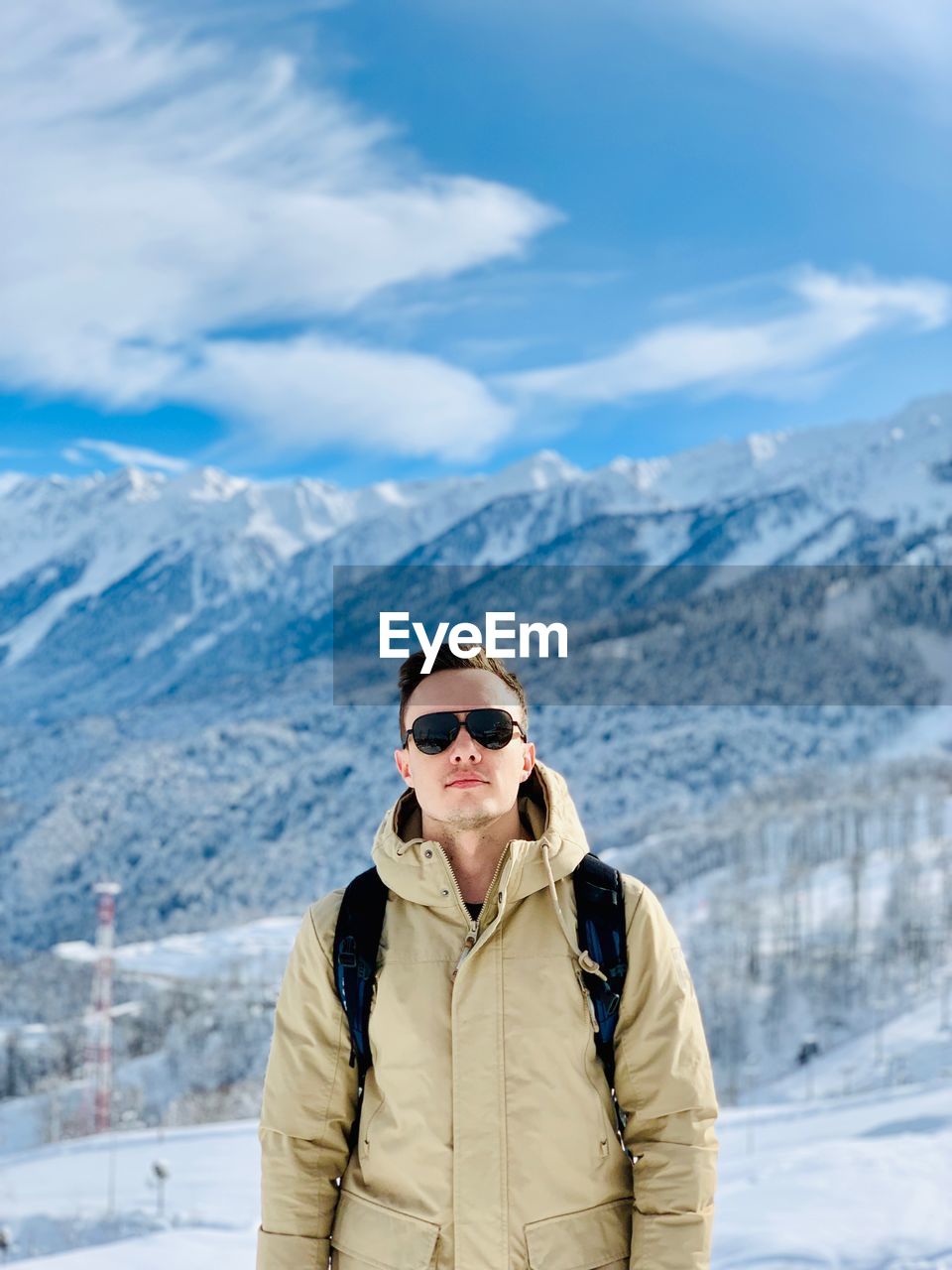 Young man standing against snowcapped mountains