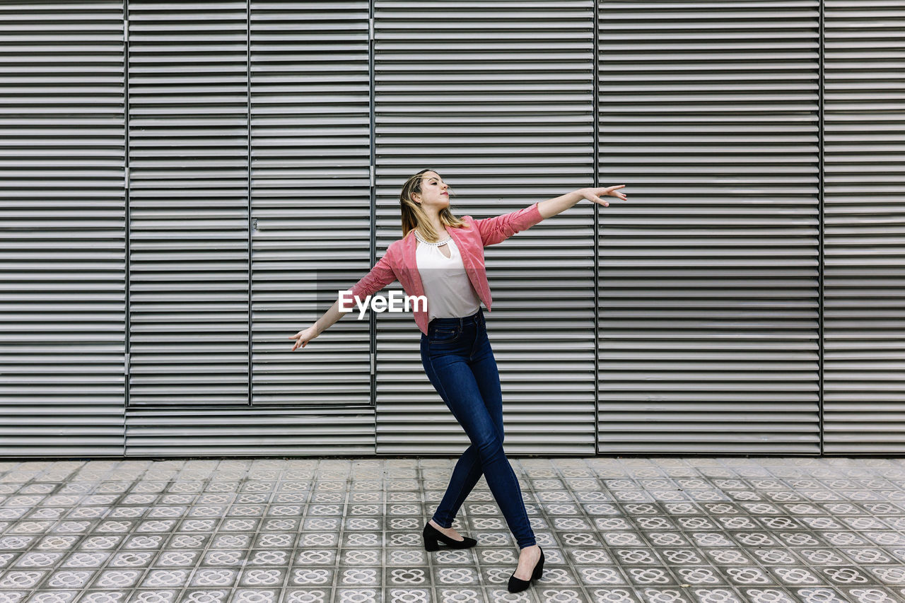 Spain, barcelona, young businesswoman dancing in city