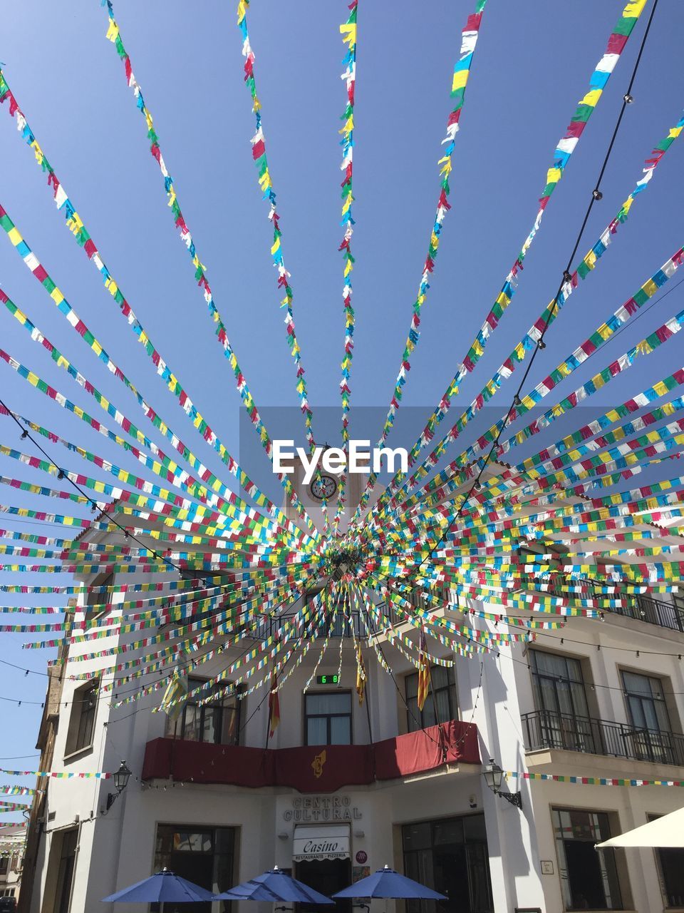 Low angle view of bunting flags hanging on building against sky