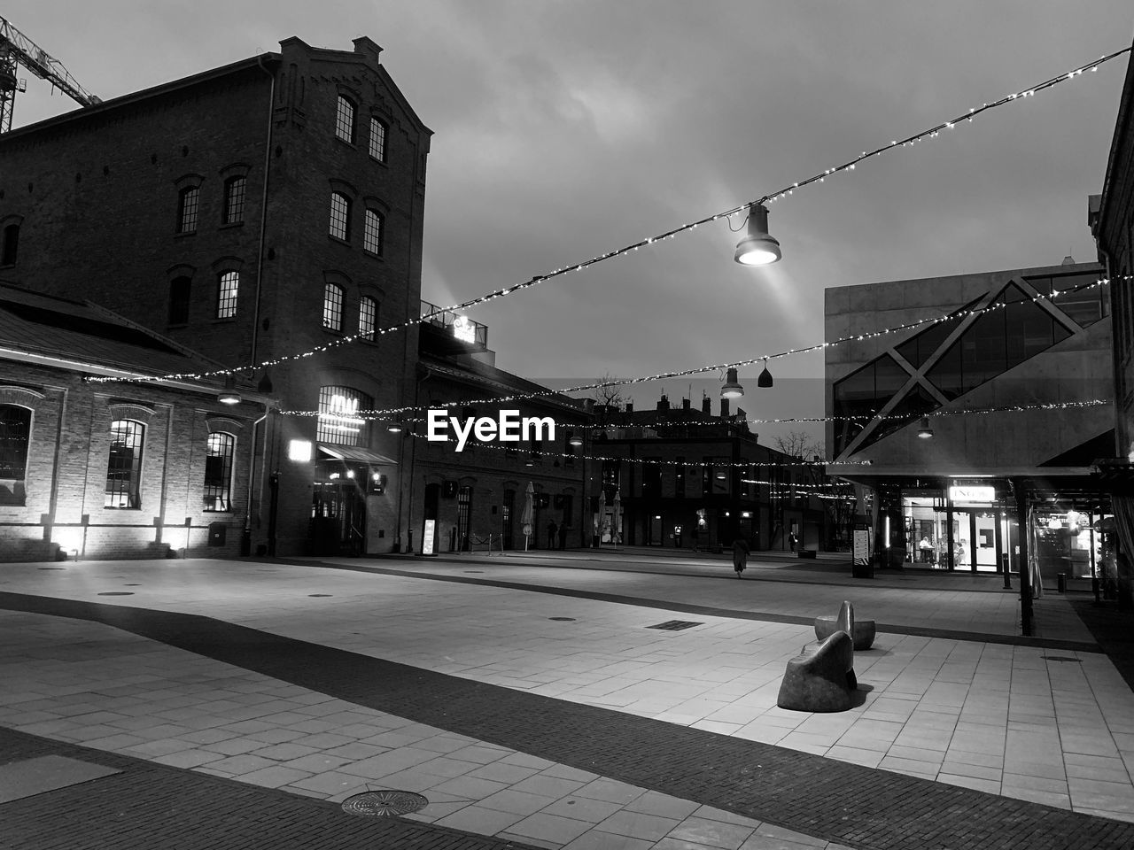 ILLUMINATED STREET AMIDST BUILDINGS AGAINST SKY