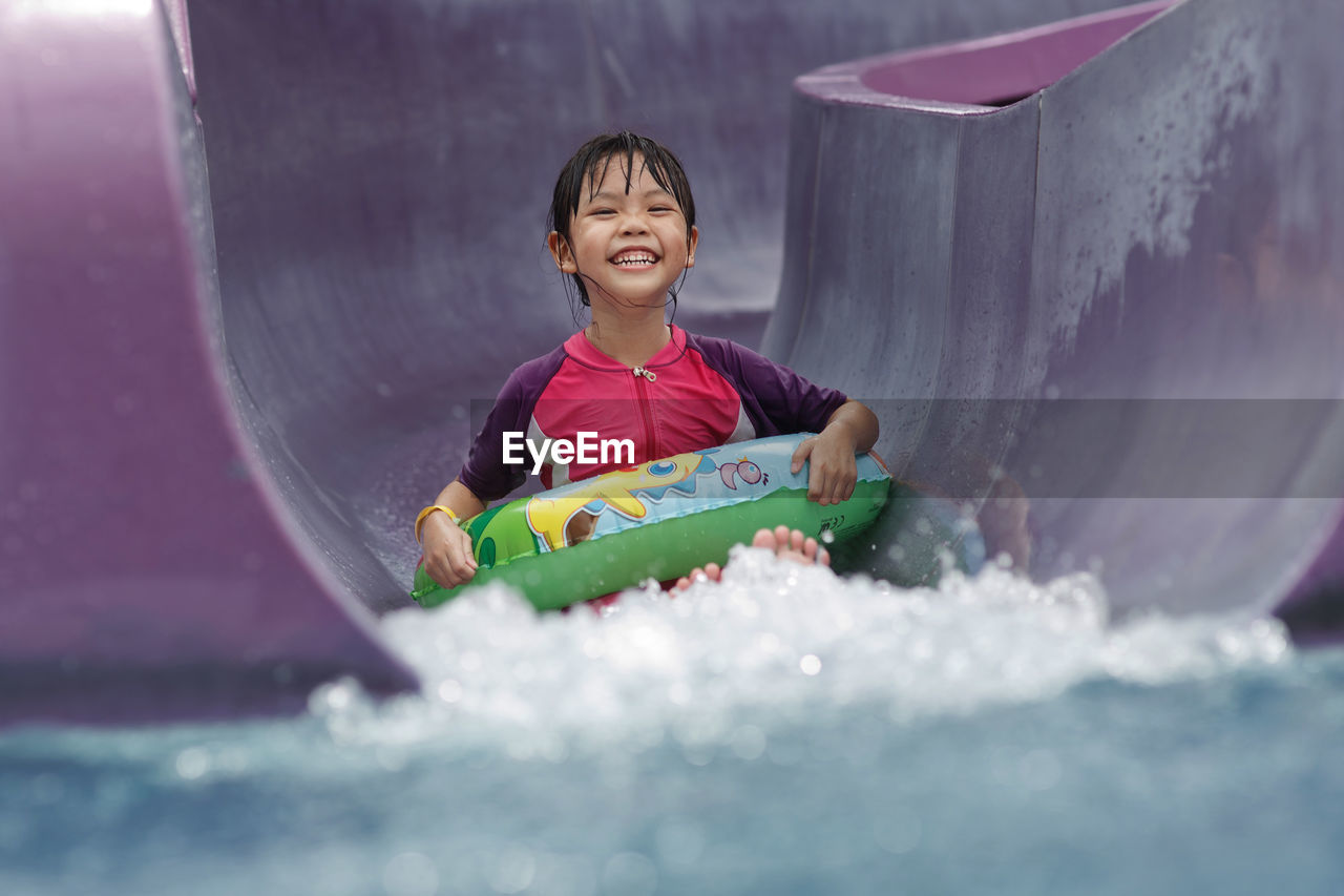 Portrait of girl sliding down in water slide at water park