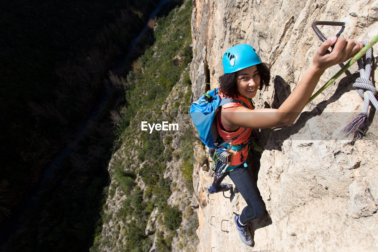 Young woman climbing through a via ferrata in chulilla canyon (spain)