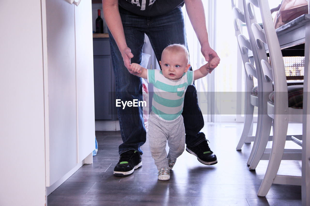 Low section of father and son walking at home