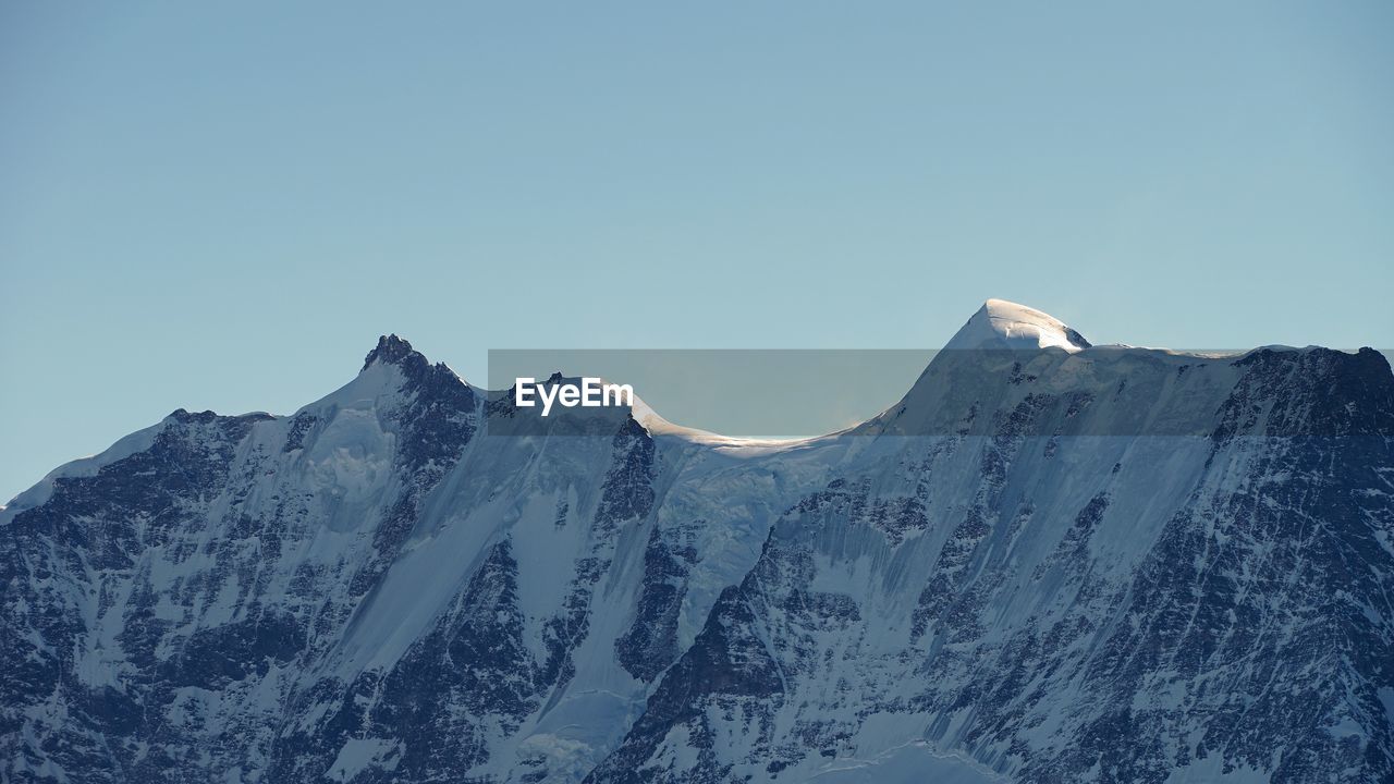 Scenic view of snowcapped mountains against clear sky