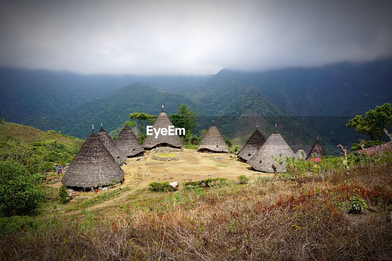 High angle view of traditional houses on hill against mountains during foggy weather