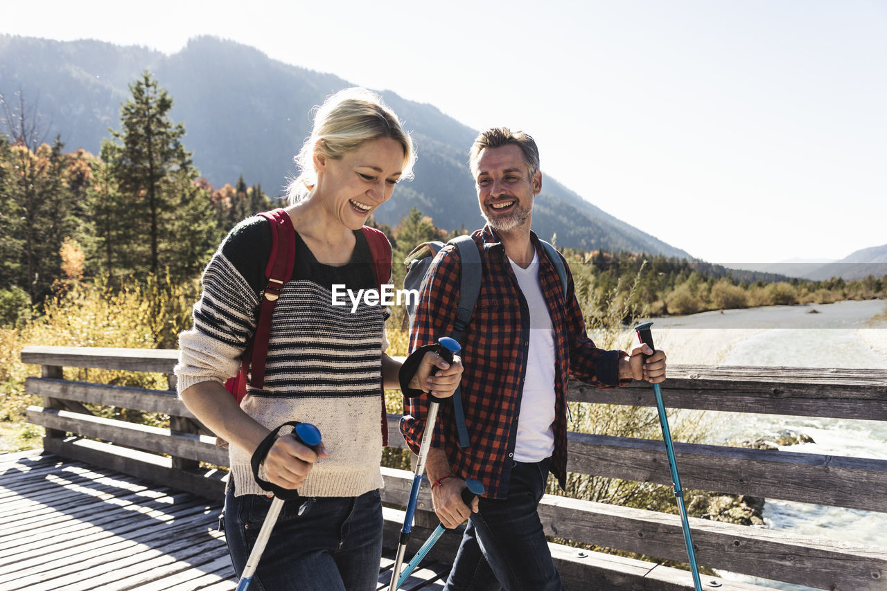 Austria, alps, happy couple on a hiking trip crossing a bridge