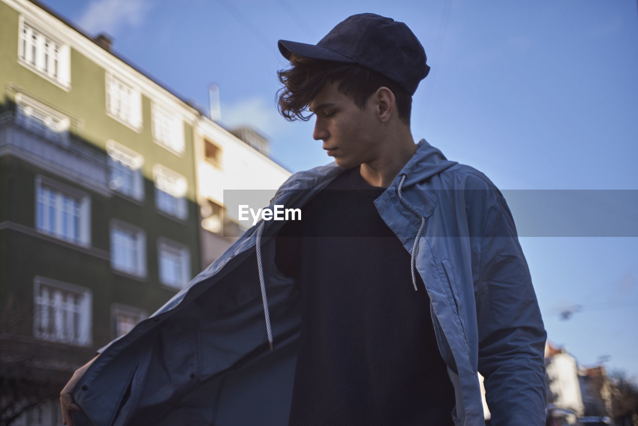 Young man standing in city against sky