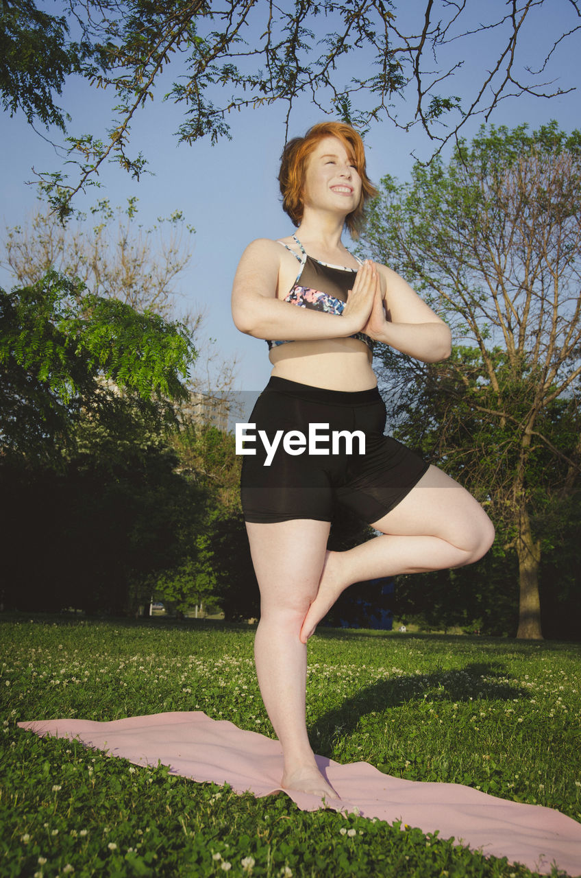 Low angle view of woman practicing tree pose yoga at park