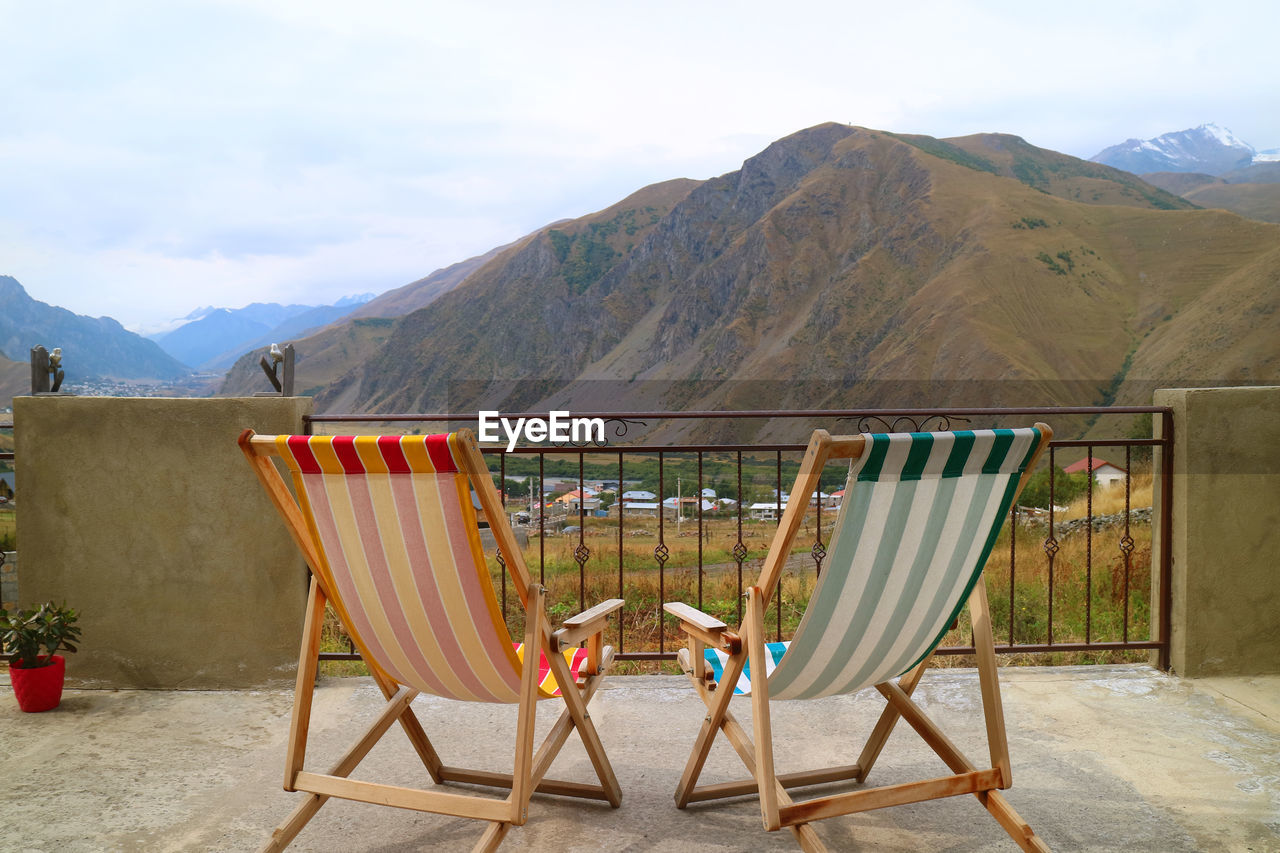 Pair of empty deck chairs at the veranda against beautiful mountain view