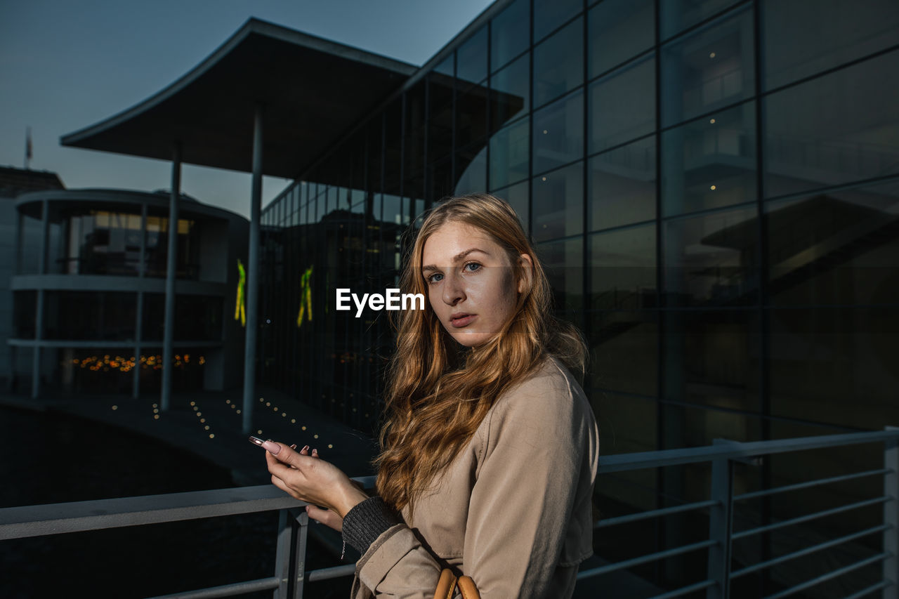 Portrait of woman standing against building