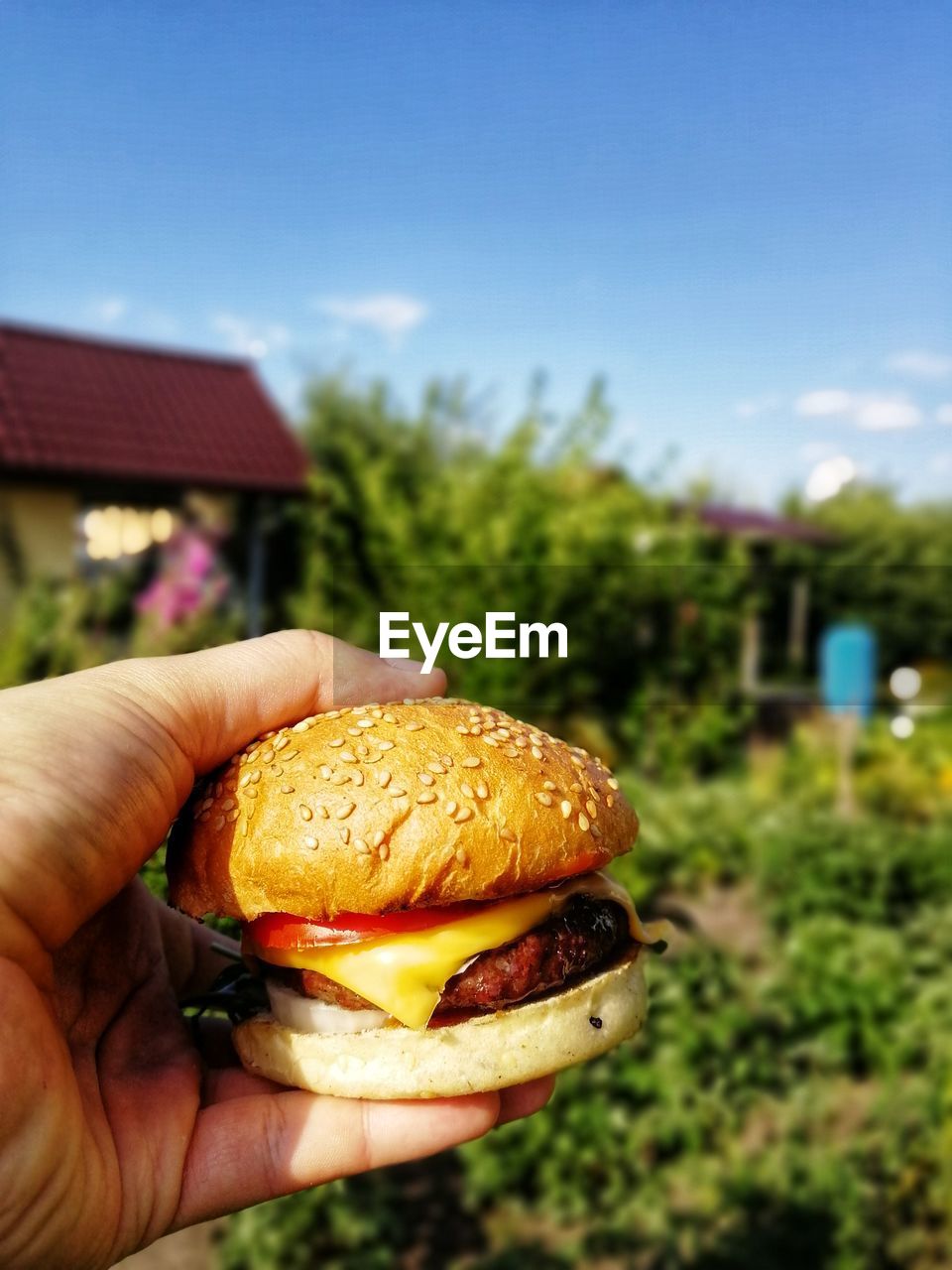 Cropped image of person holding burger cone against sky