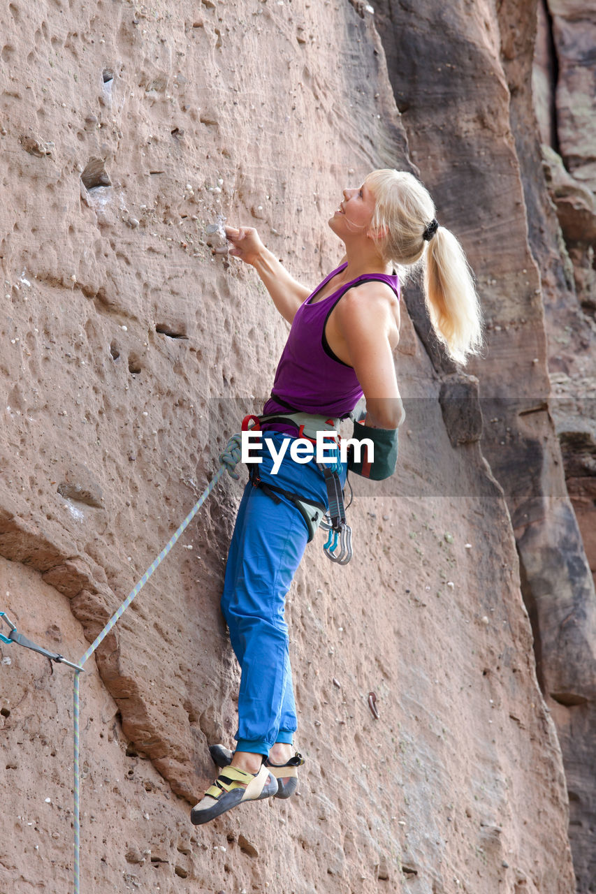 Young blonde woman climbing an extreme diffcult rock - veronika frank at rötzenstein - pfalz