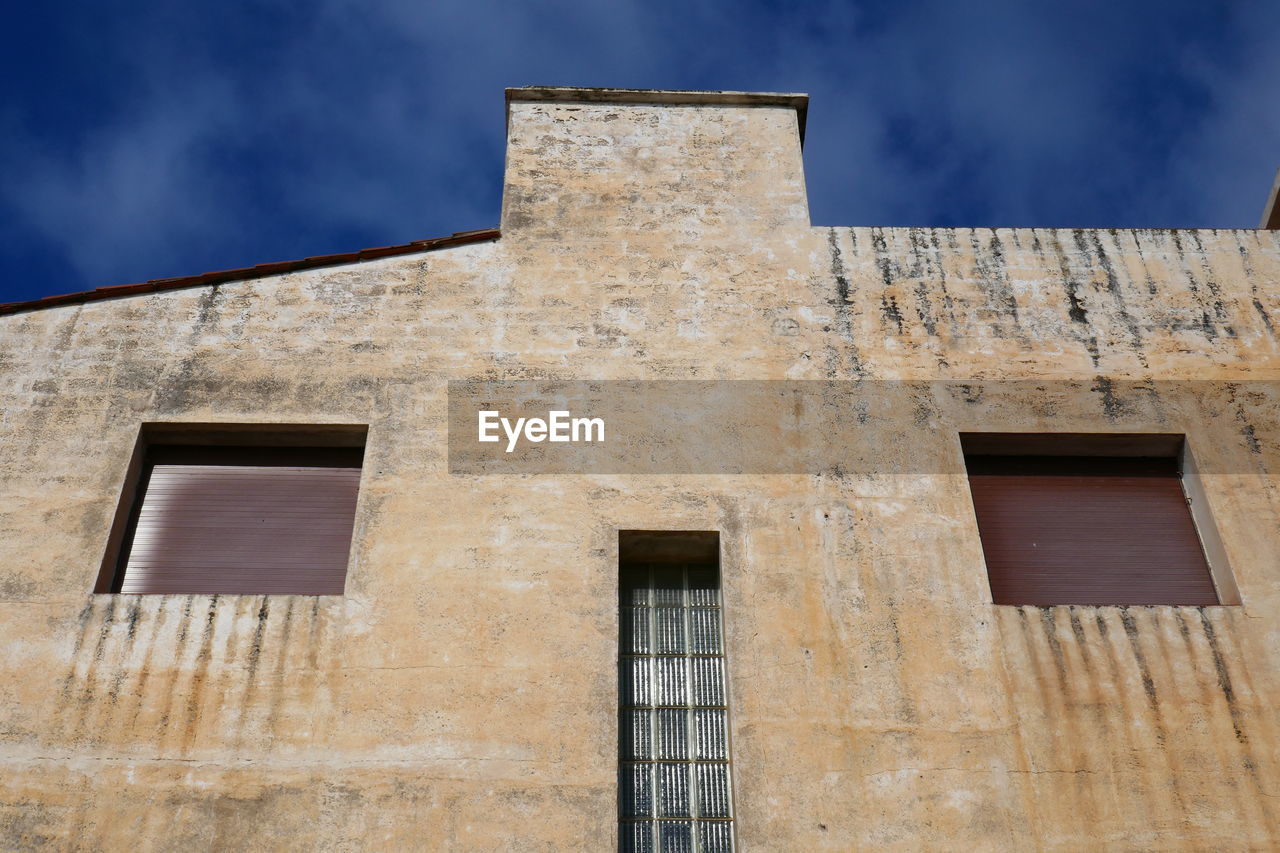 Low angle view of face on old building against sky