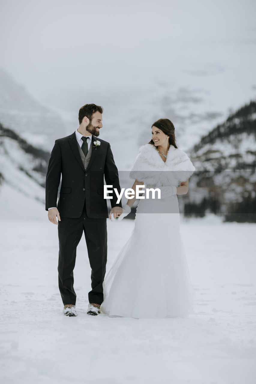 Bride and groom in love on ice on frozen lake in mountains in winter