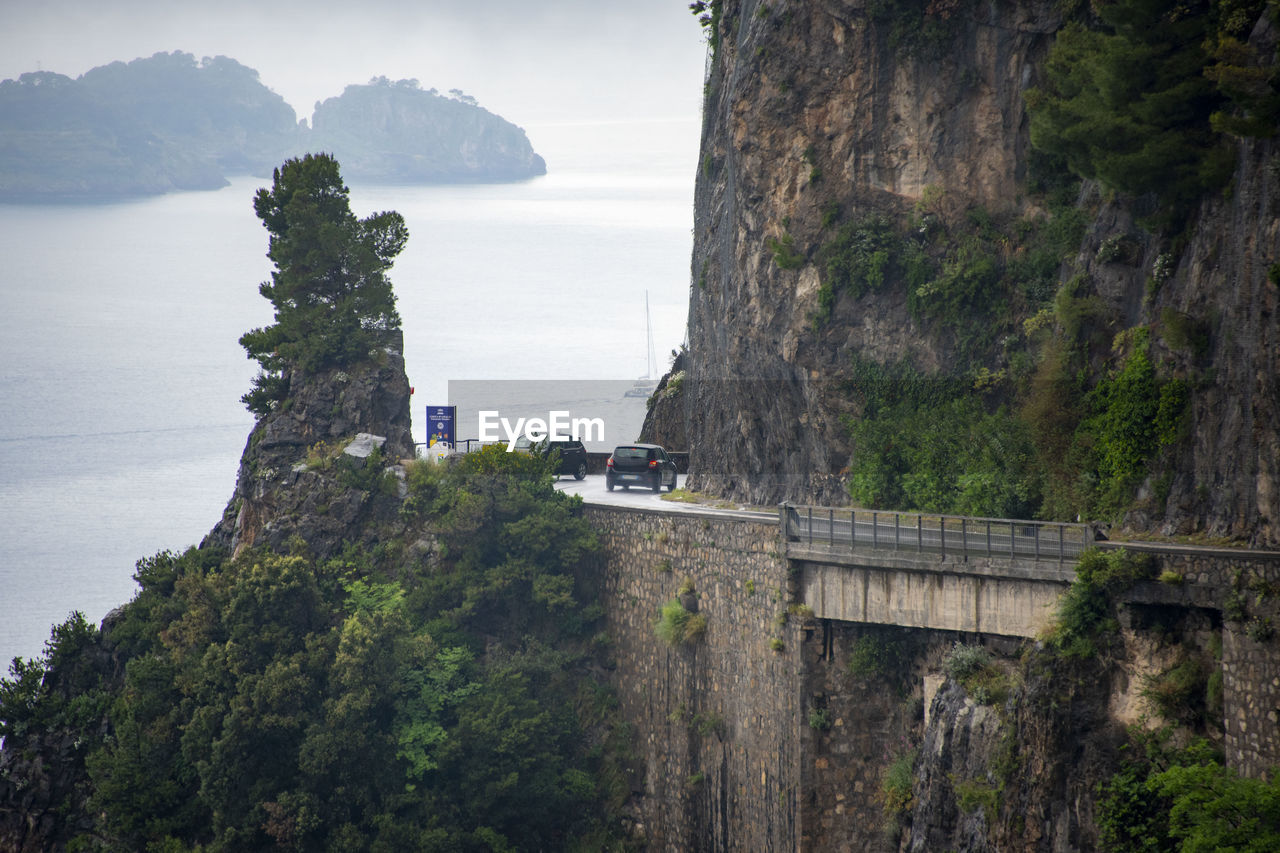water, cliff, sea, architecture, nature, land, coast, tree, plant, travel, scenics - nature, travel destinations, built structure, environment, mountain, beauty in nature, terrain, beach, sky, landscape, tourism, outdoors, history, no people, coastline, rock, the past, tranquility, holiday, trip, vacation, day, building, building exterior, bay, transportation, high angle view, tranquil scene, landmark, fog