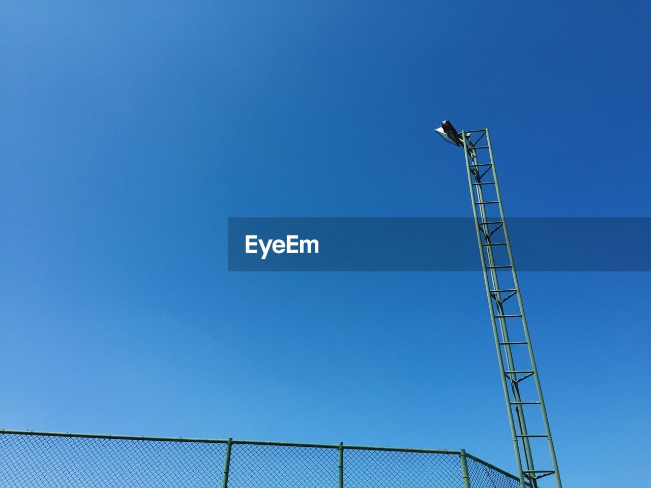 Low angle view of lighting equipment against clear blue sky on sunny day