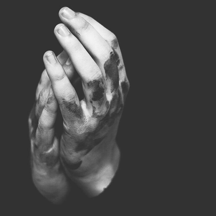 Close-up of clasped hands against black background