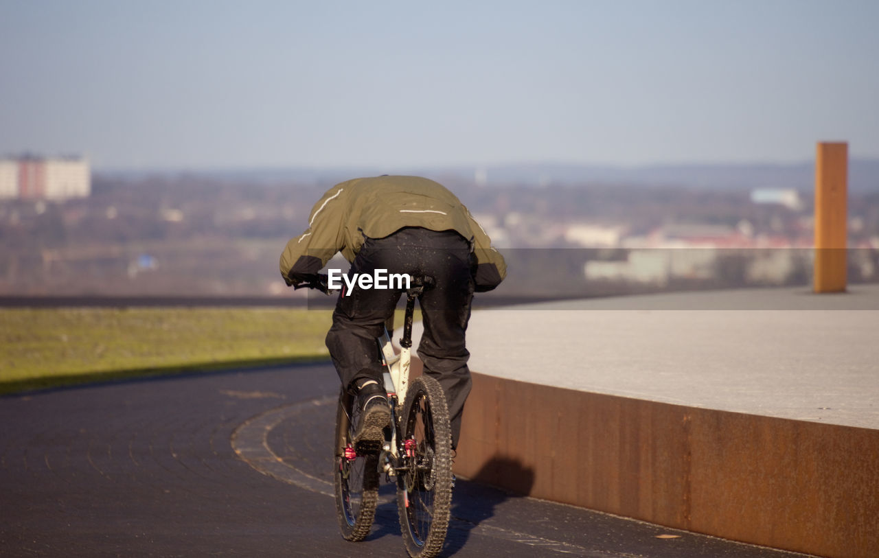 Rear view of man riding bicycle on road