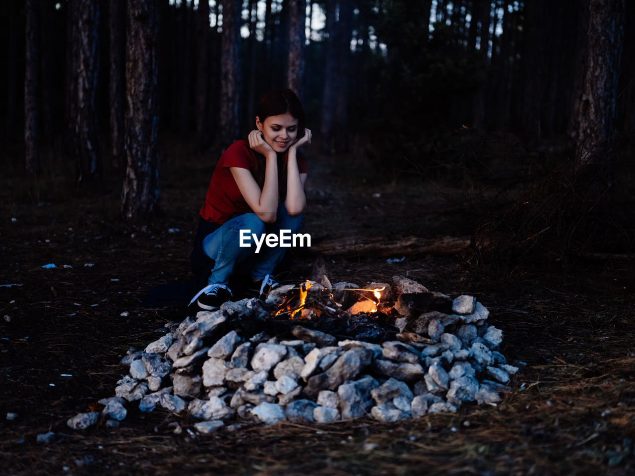 Full length of man sitting on log in forest