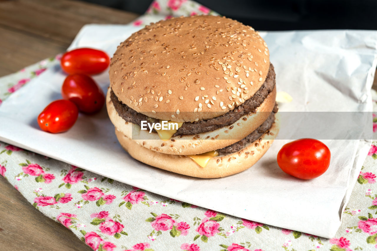 High angle view of hamburger with tomatoes on paper over table