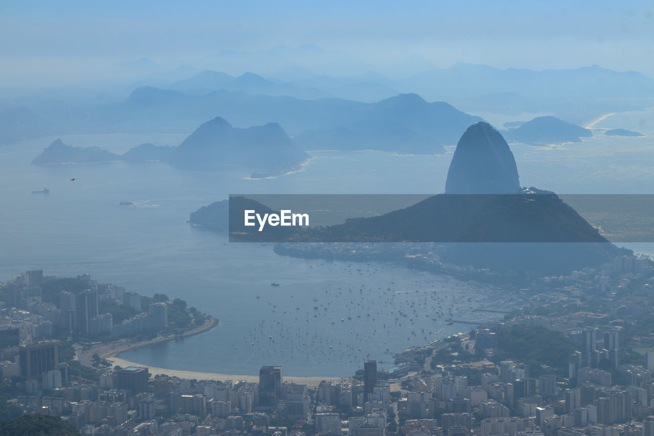 HIGH ANGLE VIEW OF SEA AND BUILDINGS IN CITY