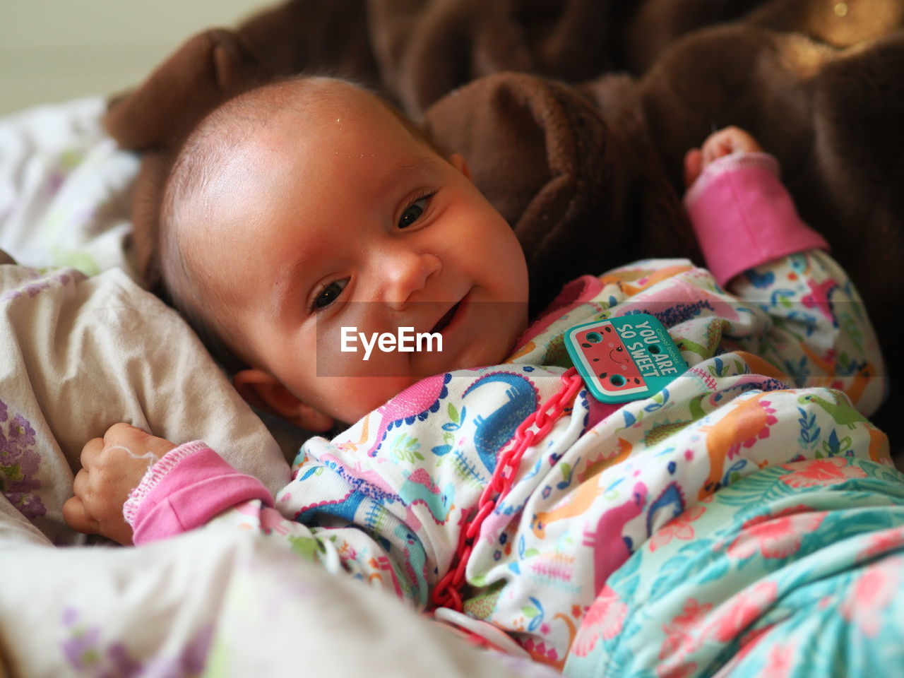 Portrait of cute baby girl lying on bed