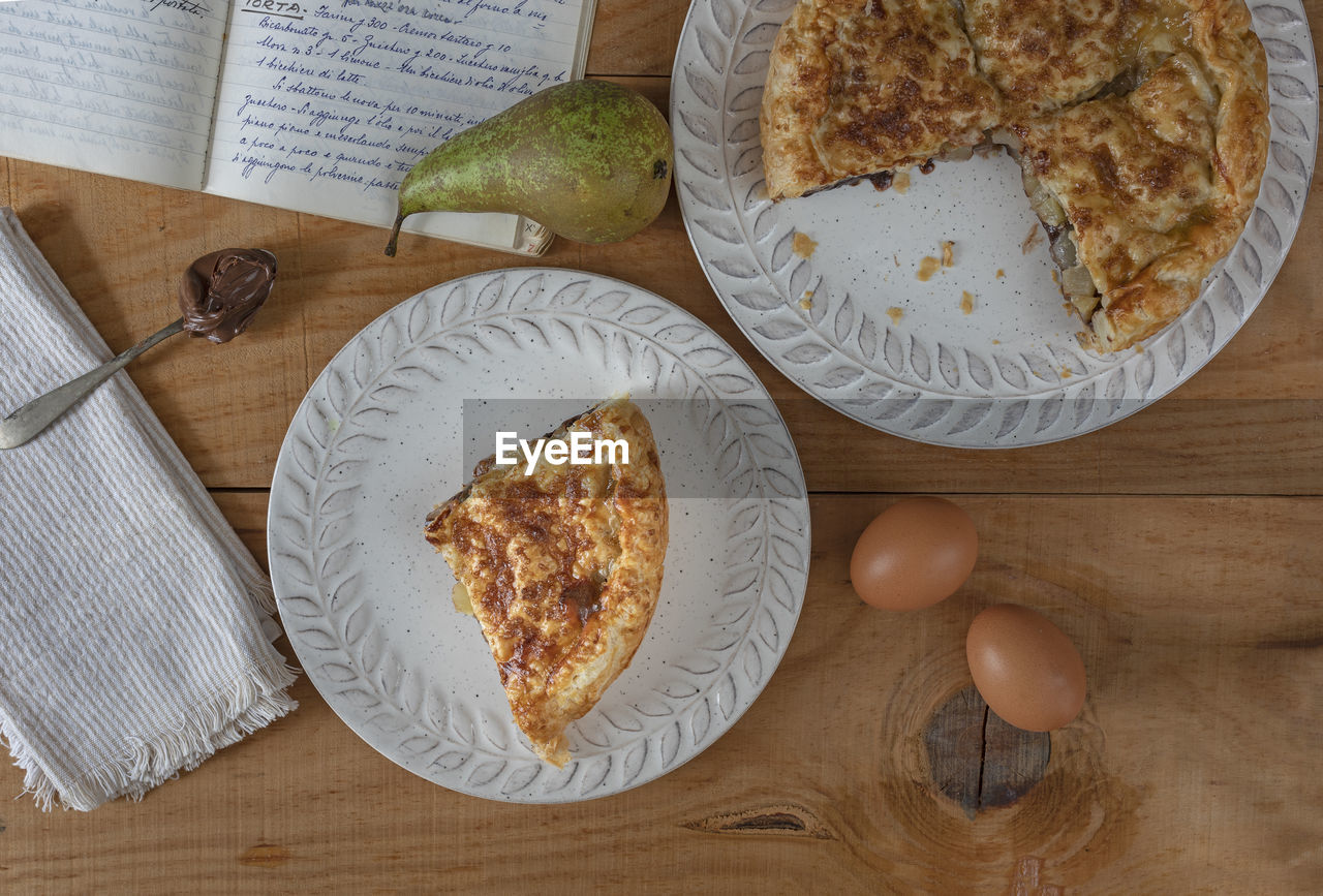 Slice of puff pastry cake and pears on a wooden table.  recipe book written in beautiful handwriting