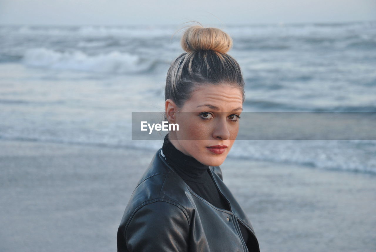 Side view portrait of confident woman with hair bun standing at beach