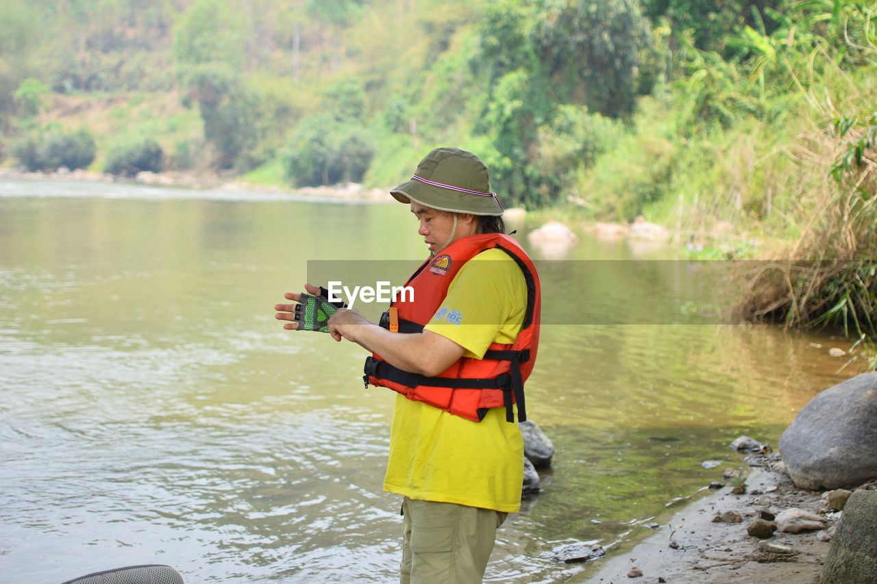 MAN STANDING IN RIVER WITH BOAT