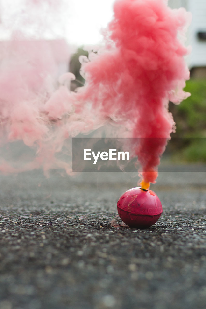 Close-up of pink smoke bomb on road