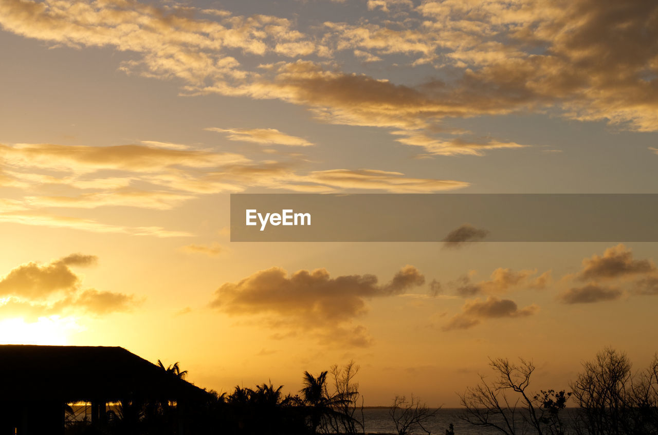 Beautiful sunset with some clouds and the silouhette of the building on the beach