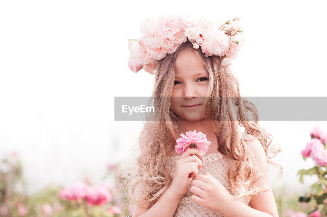 pink, flower, flowering plant, women, plant, one person, portrait, child, hairstyle, nature, long hair, childhood, beauty in nature, clothing, smiling, innocence, portrait photography, looking at camera, happiness, female, freshness, crown, fashion, cute, royalty, emotion, summer, bride, copy space, front view, dress, wreath, adult, outdoors, looking, laurel wreath, springtime, person, brown hair, young adult, spring, blossom, toddler, positive emotion, blond hair, headshot, fashion accessory, holding, flower arrangement, day, lifestyles, rose, tiara, waist up, fun, fragility, contemplation