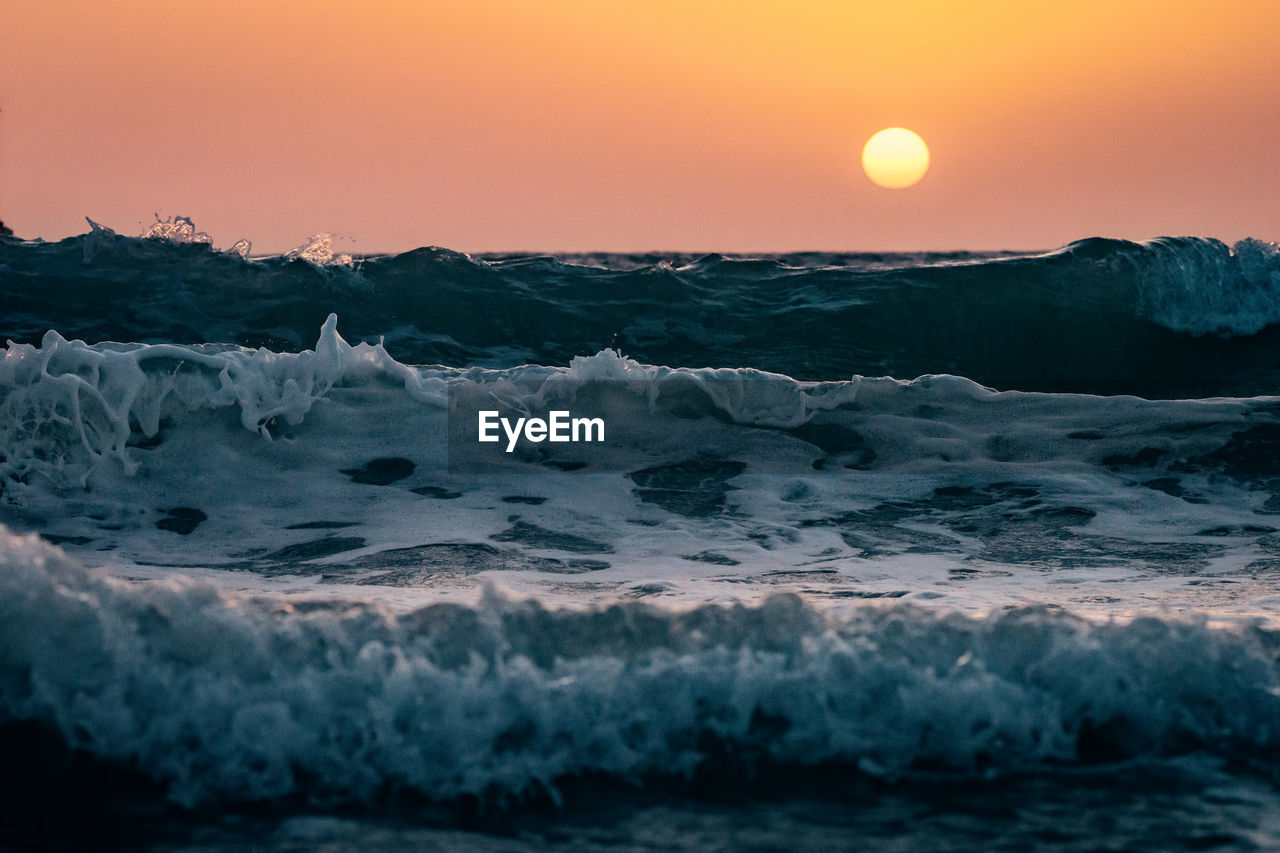 Scenic view of sea waves against sky during sunset