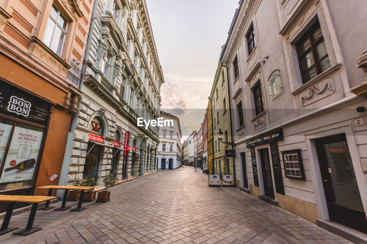 NARROW STREET AMIDST BUILDINGS AGAINST SKY