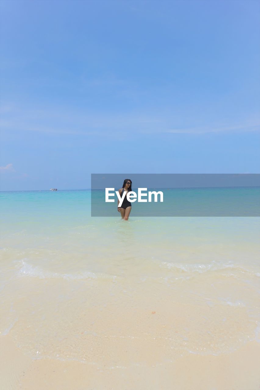 Woman amidst sea against sky