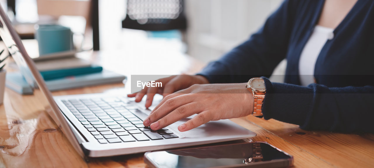 MIDSECTION OF MAN USING LAPTOP