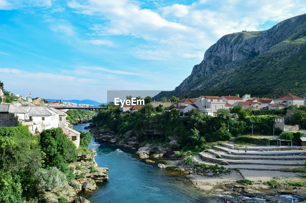 River amidst buildings and mountains against sky