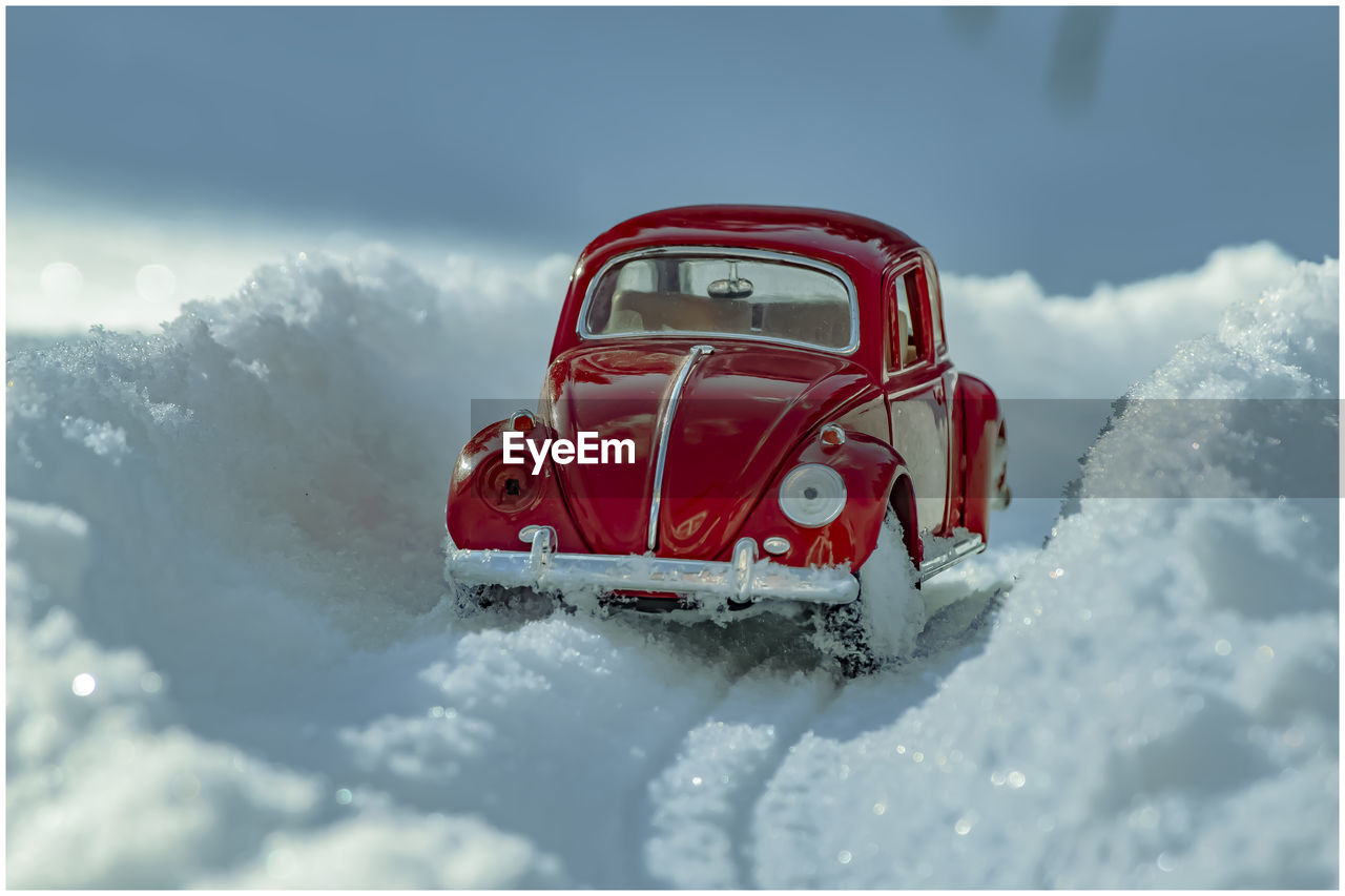 Red car in snow against sky