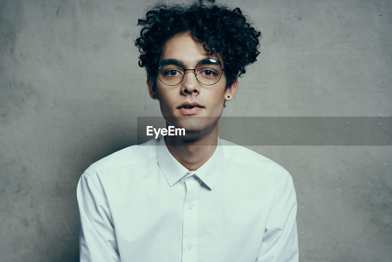 Portrait of young man standing against wall