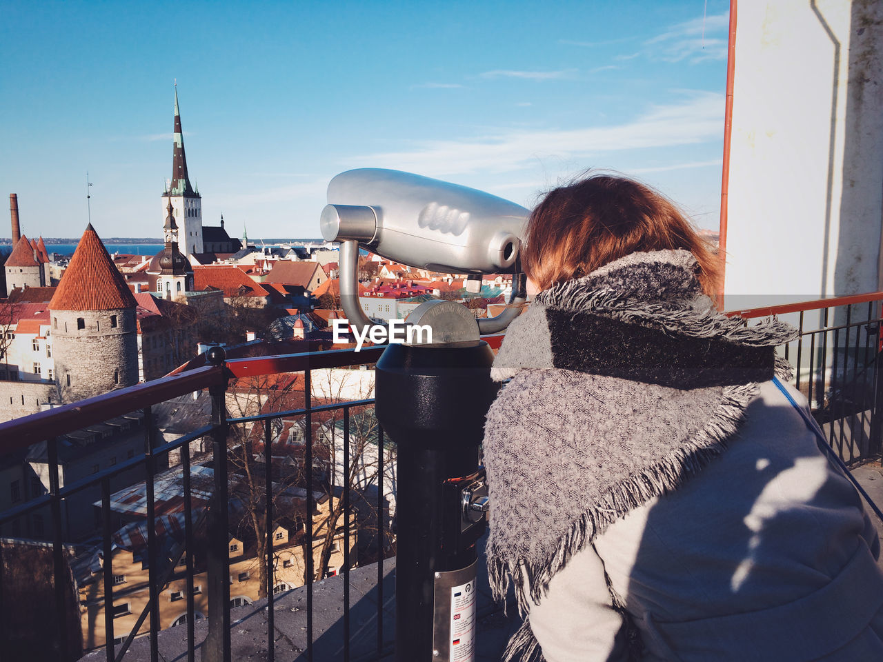 Woman looking through coin-operated binoculars in city