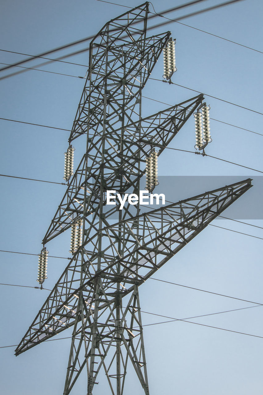 Low angle view of electricity pylon against clear blue sky