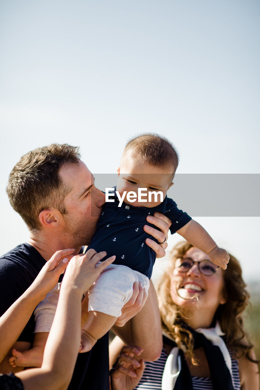 Dad holds & kisses son as family looks on