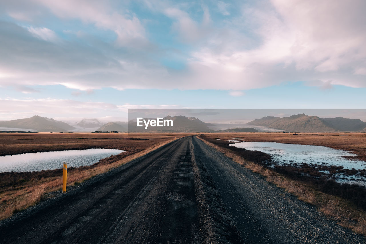 Diminishing perspective of empty road against cloudy sky