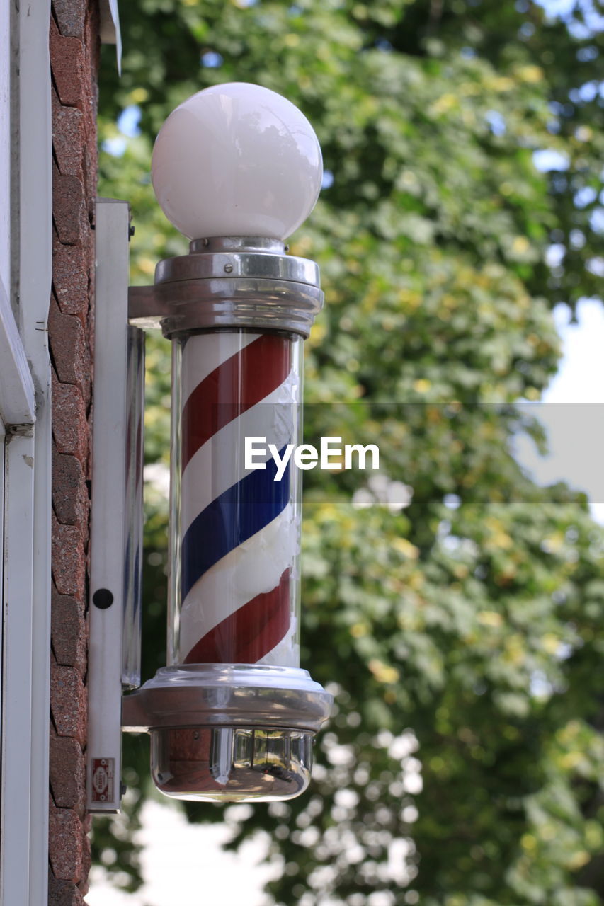 Low angle view of barber pole against trees