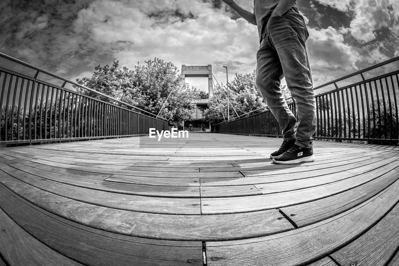 black and white, one person, monochrome, monochrome photography, black, architecture, railing, sky, white, leisure activity, footwear, lifestyles, men, cloud, built structure, skateboarding, day, skateboard, casual clothing, low section, nature, sports, adult, fisheye lens, motion, city, full length, balance, person, human leg, skateboard park, jeans, outdoors, standing, clothing, bridge, rear view, tree, skill, skate shoe, footpath