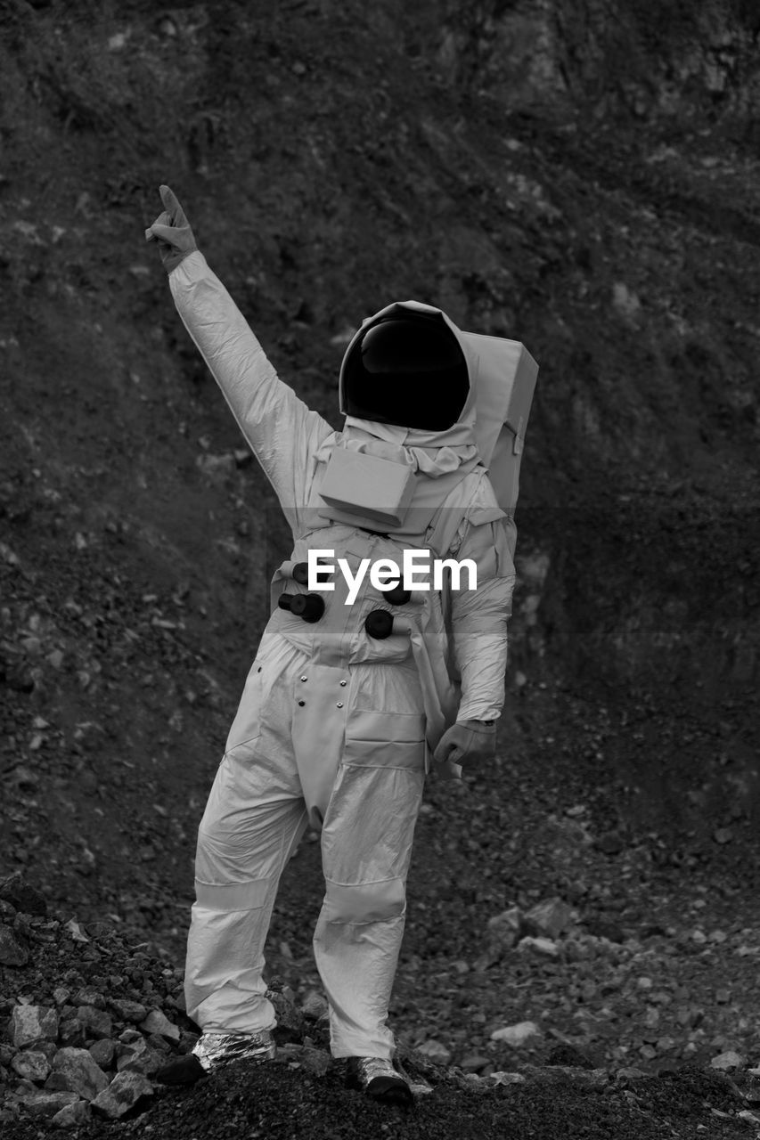 Full length of person in astronaut costume while pointing on field