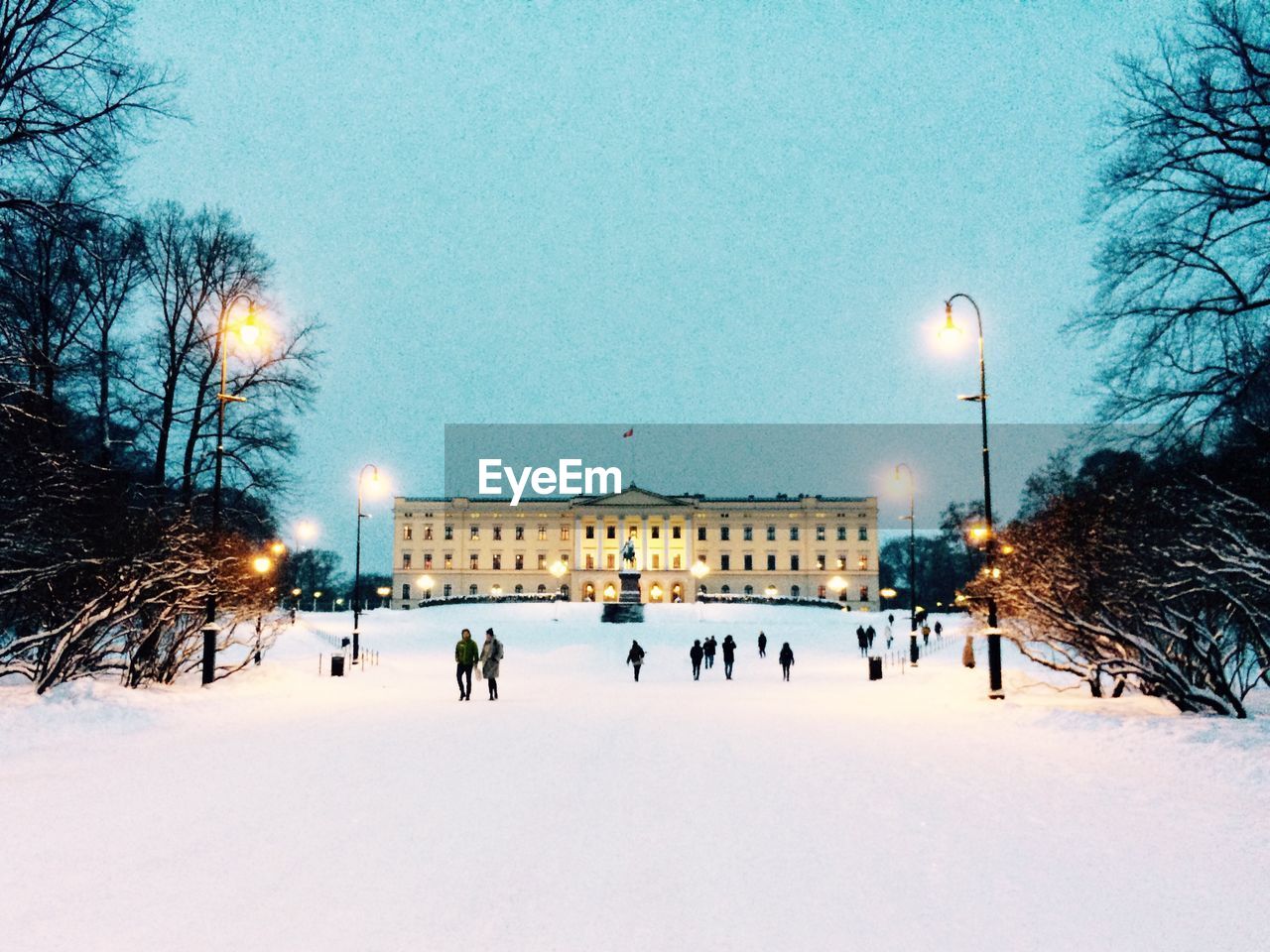 People on snow covered land outdoors royal palace at dusk