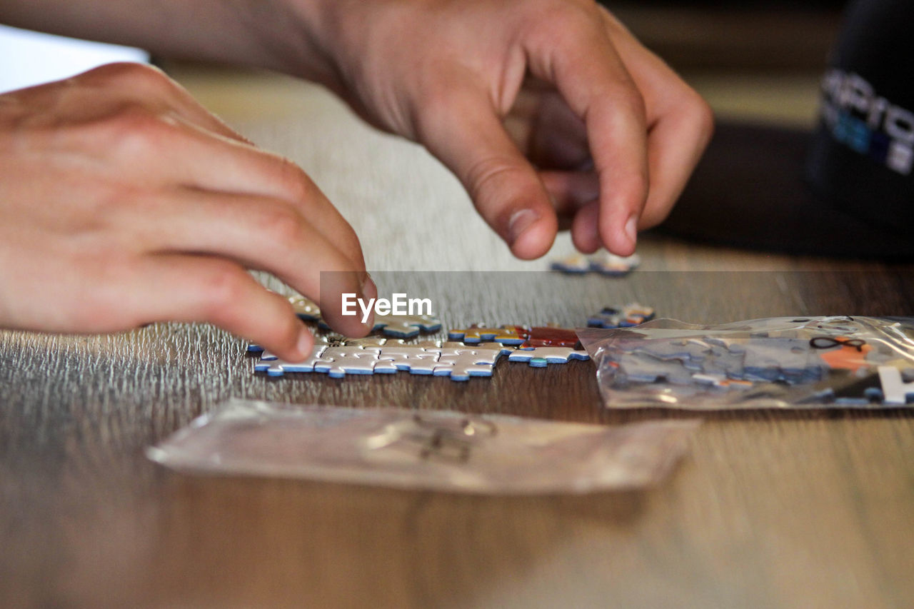 Cropped image of person playing with jigsaw puzzle on table