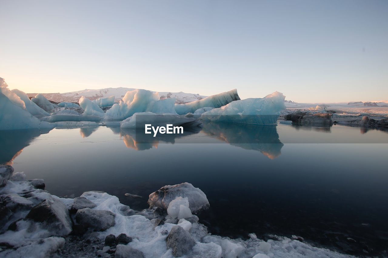 Frozen lake against clear sky during winter